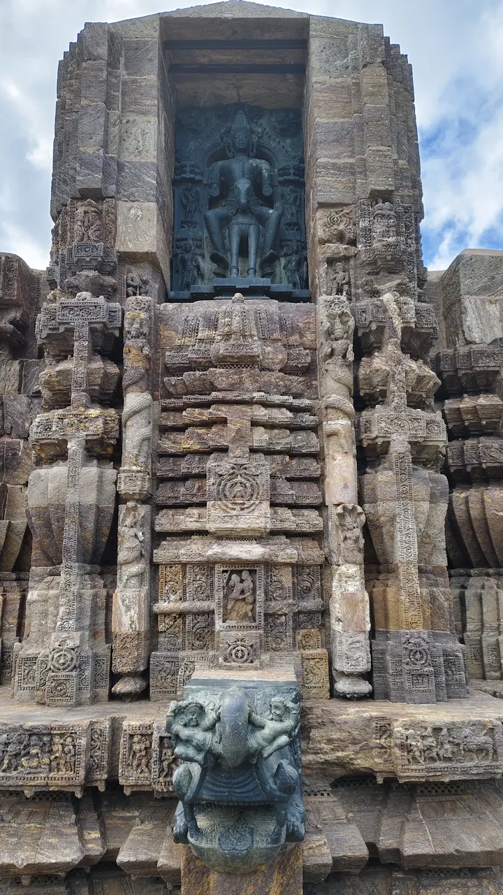 Detaillierte Steinschnitzereien am Sonnentempel in Konark, Indien, mit einer zentralen Götterstatue, feiner Reliefarbeit und einer markanten Elefantenskulptur.
